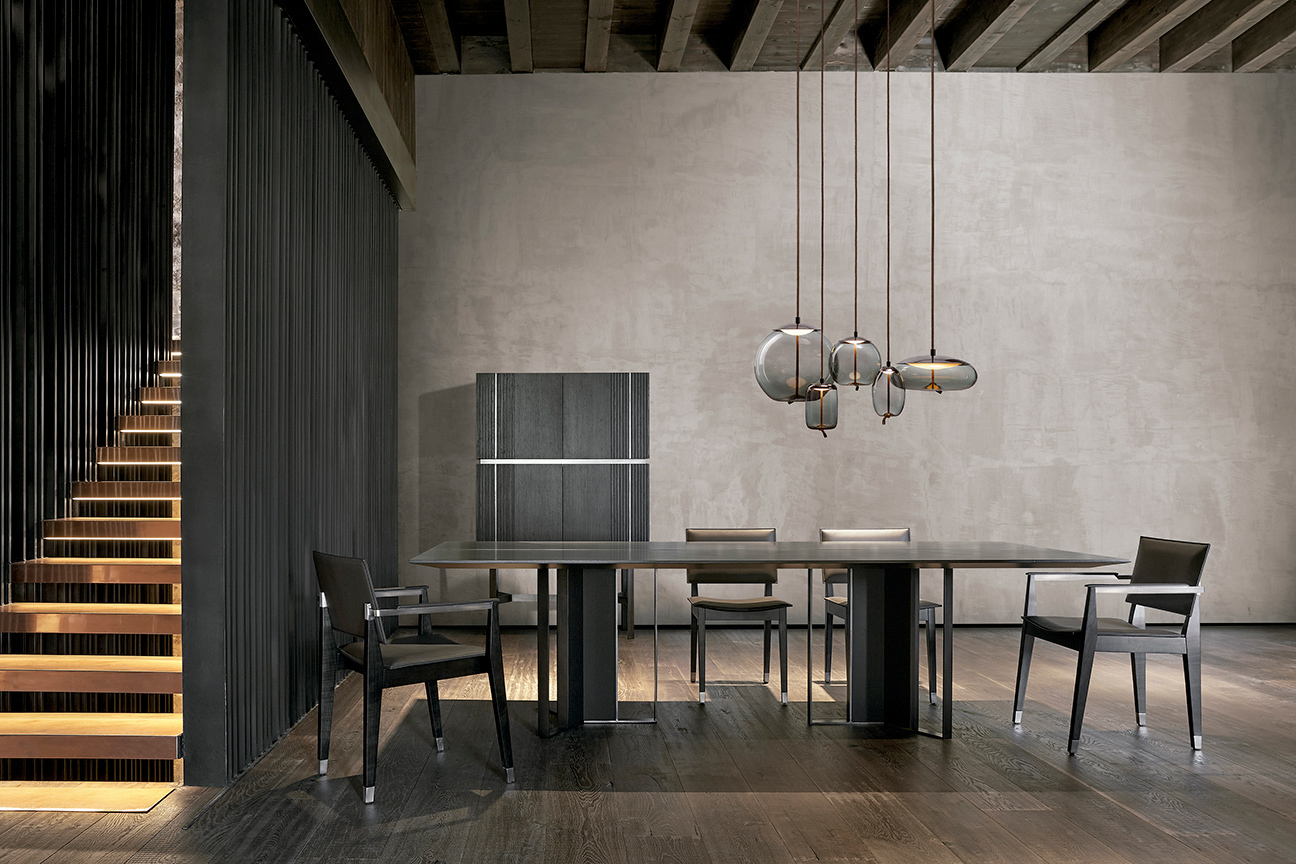 Comedor moderno en tonos oscuros y negro, compuesto por sillas de piel y mesa de diseño de Ramón Esteve.